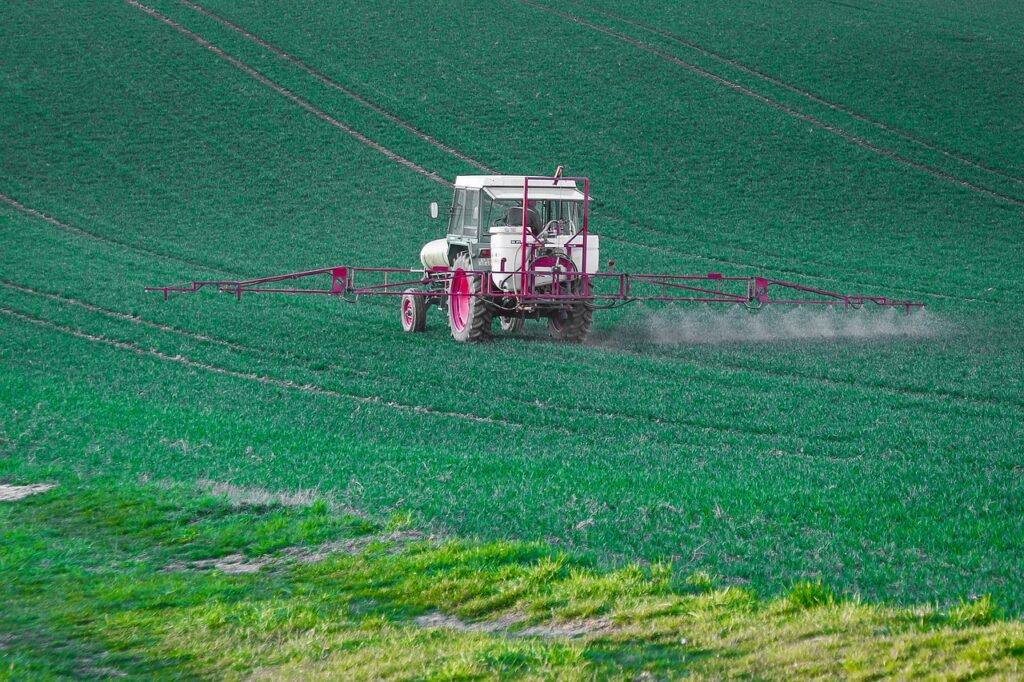 Farm equipment spraying pesticide on fields