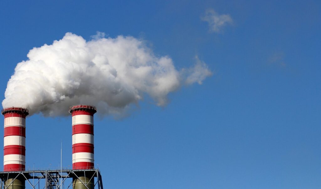 smokestacks with billowing smoke against a blue sky