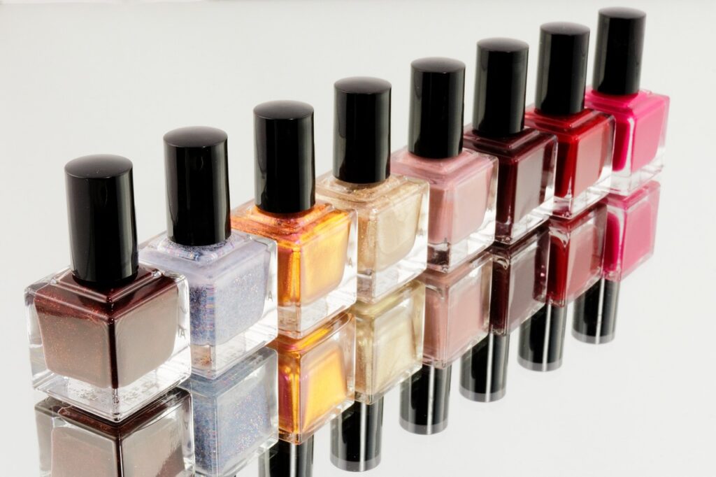 row of nail polish bottles on reflective countertop
