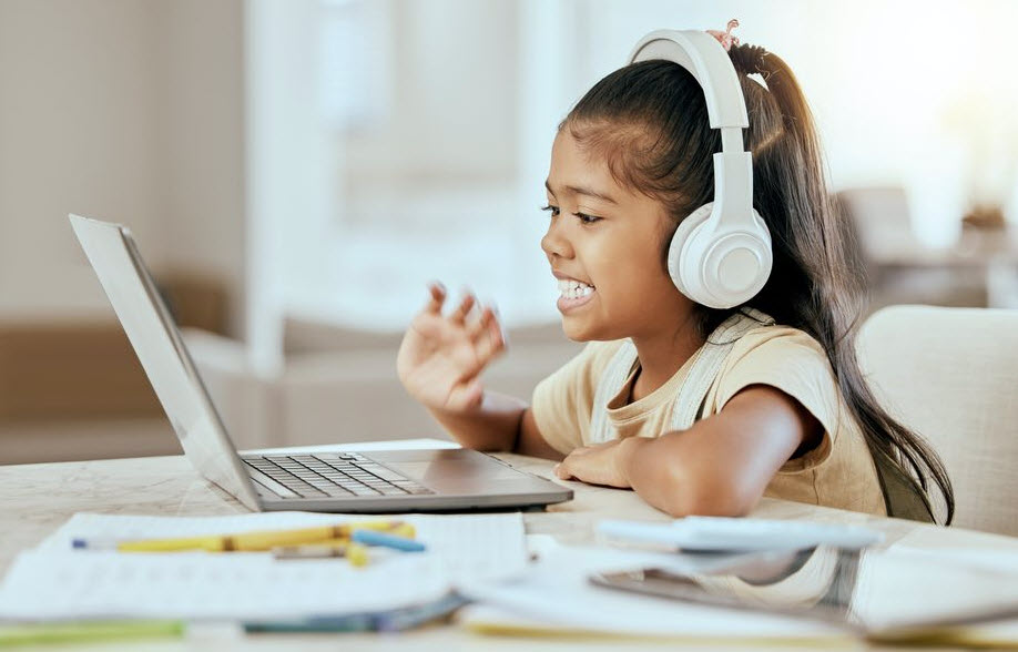 yopung girl wearing headphones while sitting in front of laptop computer